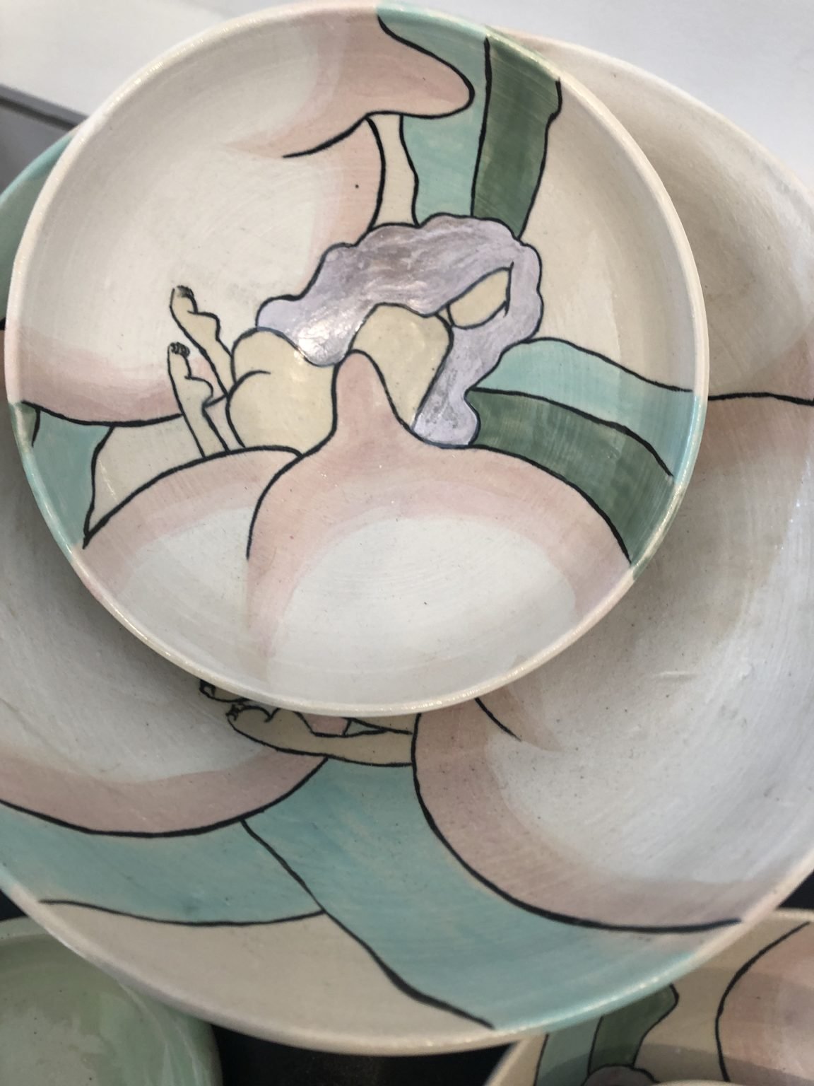 up shot of handpainted bowl with a naked girl and a peach on it